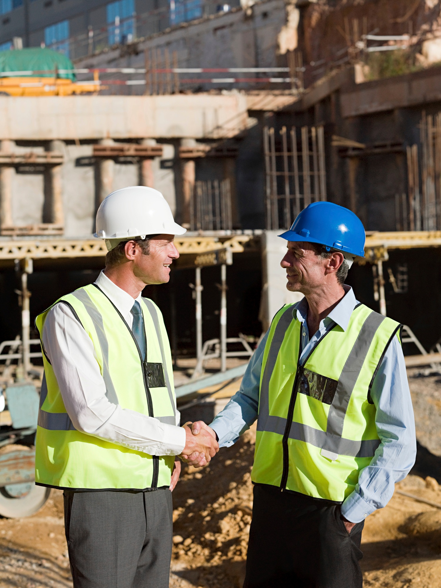 Two construction workers shaking hands on a building site