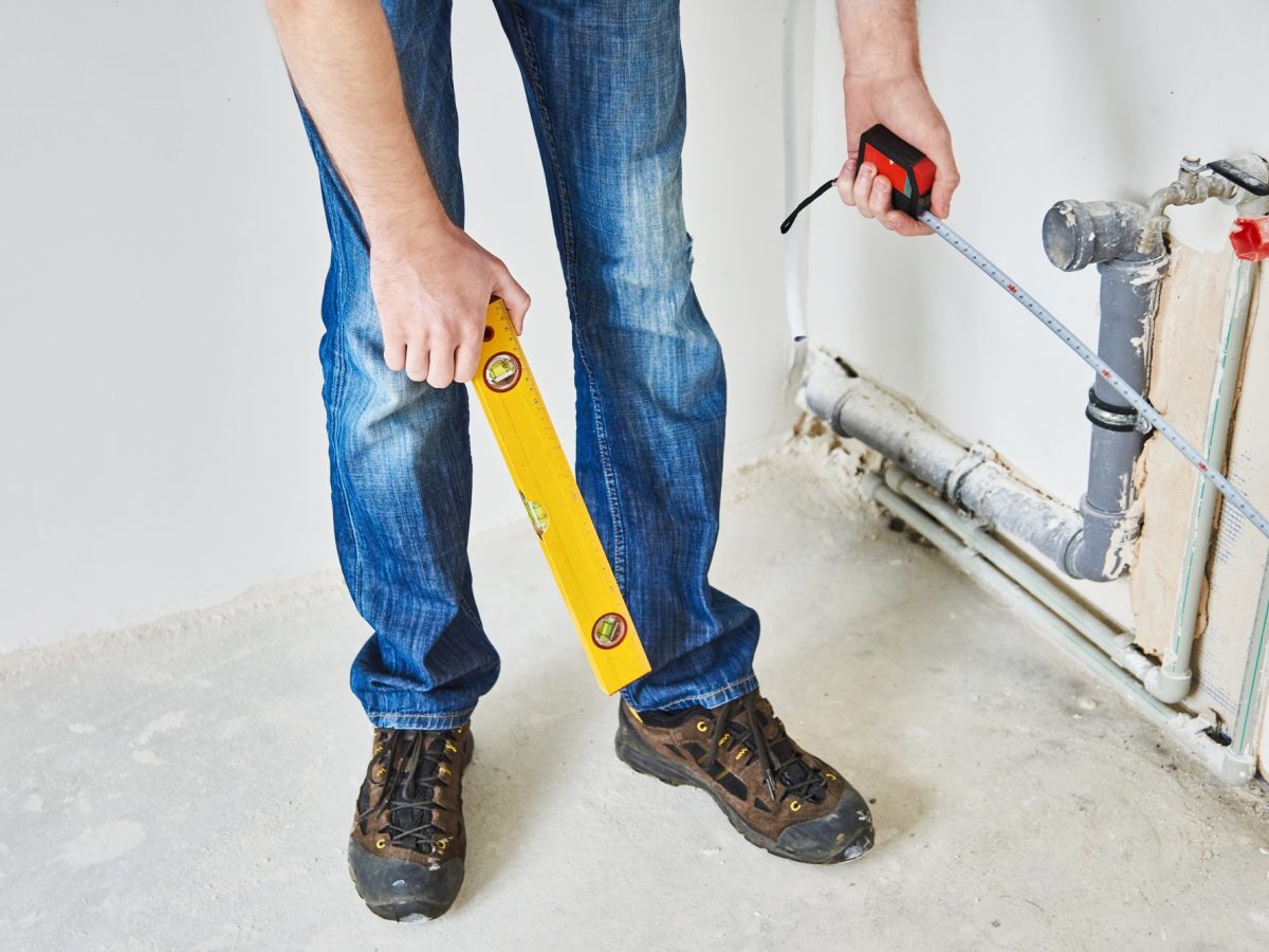 Plumber checks pipe vertical level after installation.